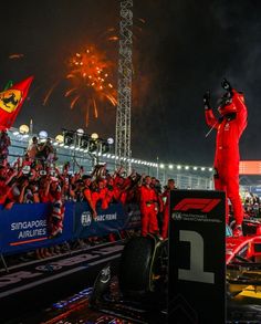 the race car driver waves to the crowd as he stands on top of his car