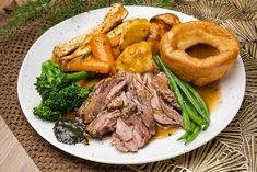 a white plate topped with meat and veggies on top of a woven place mat