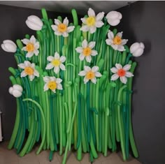 a bunch of flowers that are in the shape of green stems with white and yellow flowers on them