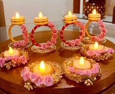 a table topped with lots of candles on top of a wooden table covered in pink flowers