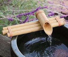 a wooden spigot with water pouring out of it and lavender flowers in the background