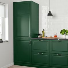 a kitchen with green cabinets and white walls