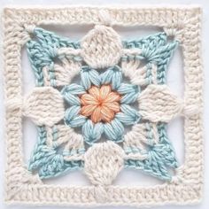 a crocheted square with an orange flower in the center and two rows of smaller squares on each side