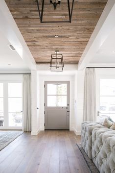 a living room filled with furniture and a wooden ceiling mounted to the side of a wall