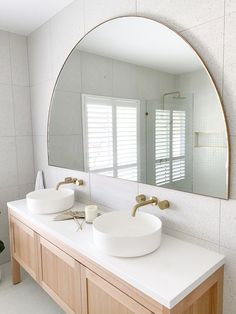 a bathroom with two sinks and a large round mirror above it's countertop