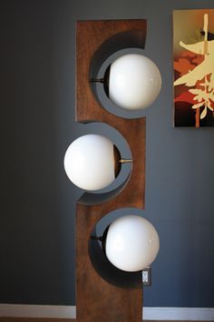 three lights are mounted on the wall near a painting