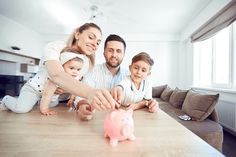 a man, woman and two children are playing with a piggy bank on the table