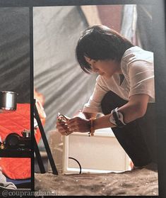 a woman kneeling down next to a small white box with a camera on it's side