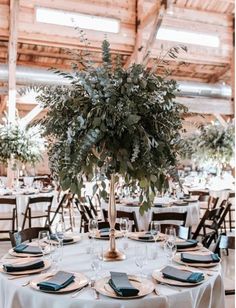 a table set with plates, place settings and greenery in a rustic barn setting