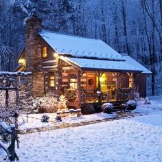 a cabin in the woods is lit up with christmas lights and surrounded by snow covered trees