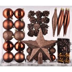 an assortment of christmas ornaments and decorations in a clear display case with gold stars, pine cones, brown baubs