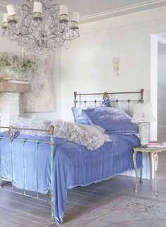 a bedroom with a blue bed and chandelier