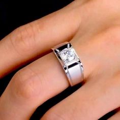 a woman's hand with a white diamond ring on her left hand and the other hand holding an engagement ring