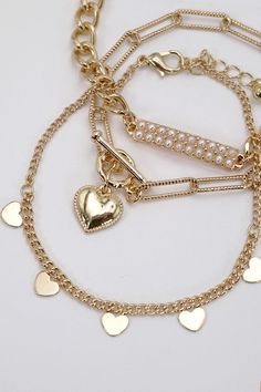 Pearl Stud Bar Heart Link Multi-Chain Bracelet Set, a captivating ensemble that beautifully combines classic pearls, modern bar details, and heart-shaped links for a unique and stylish accessory. Pearl Stud Accents: Each bracelet in this set features lustrous pearl studs. The heart-shaped links connect the various chains, infusing the bracelets with a romantic and charming vibe. The heart links serve as focal points, adding sentiment and sweetness to the overall aesthetic.DIMENSION length: 8" ex Gold Heart Beads Bracelet For Party, Elegant Pearl Heart Bracelet With Charm, Heart Shaped Pearl Bracelet, Multi Chain Bracelet, Pearls Bracelet, Gold Bracelet Set, Sunglass Chain, Focal Points, Faux Leather Belts