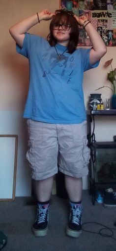 a summer outfit on a teen with shaggy shoulder length brown hair.the outfit consists of a light blue shirt with David Bowie's face and the words "David Bowie, khaki shorts, blue Patrick socks, original vans, and sunglasses on the teens head. Transmasc Outfits Plus Size, Silly Outfit Ideas, Plus Size Transmasc Fashion, Trans Summer Outfits, Trans Masc Outfits Plus Size, Summer Trans Masc Outfits, Small Town Aesthetic Outfits, Chubby Masc Outfits, Trans Masc Clothes