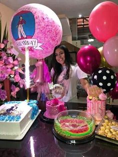 a woman standing in front of a table filled with cakes and balloons