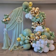 a balloon arch is decorated with gold, white and mint green balloons in the shape of a tree