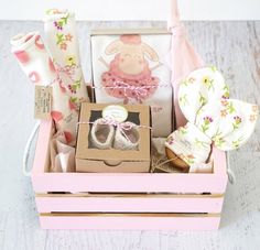 a pink box filled with baby items on top of a wooden table next to a pair of shoes