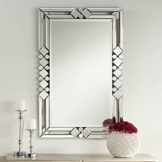 a large mirror sitting on top of a dresser next to a vase with flowers in it