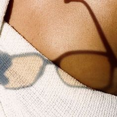 the shadow of a woman's neck and glasses on her shoulder is seen in this image