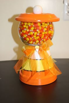 an orange candy dispenser filled with candy corn on top of a table