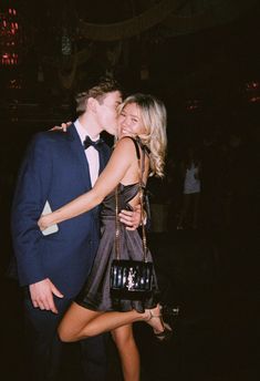 a man in a tuxedo kissing a woman on the cheek at a party