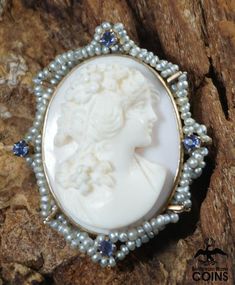 Metal: 10k Yellow Gold (.417)Weight: 8.4 gramsMeasurements: 1.25" Long; 1" Wide; 0.54" DeepMarkings: "10k"*This stunning brooch features a cameo of a finely dressed woman looking off to the right hand-carved on a pink/white shell, set into a 10k yellow gold border and bezel. The border features small pearls in two criss-crossed rows, with 4 small purple stones. The brooch features impressive high relief carving. The brooch also functions as a necklace pendant. This outstanding brooch is in great Elegant White Jewelry For Memorial, White Oval Brooch For Anniversary, White Oval Brooch For Formal Occasions, Oval Brooch Necklaces For Wedding, Hallmarked Oval Brooches For Wedding, Oval Brooch Necklace For Wedding, Heirloom White Brooch Jewelry, Victorian Cabochon Jewelry For Wedding, Medallion Shaped Brooch For Wedding