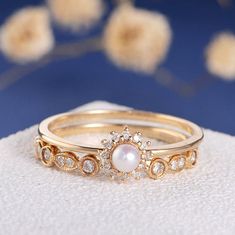 two gold rings with white pearls and diamonds on the sides, sitting on top of each other