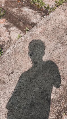 a shadow of a person standing on top of a rock