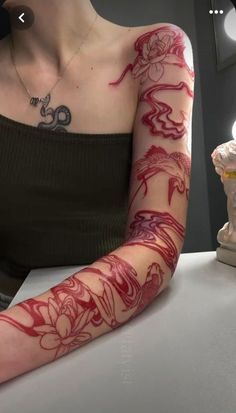 a woman with tattoos on her arm sitting at a table