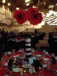 the table is set with plates, silverware and red poppies in vases