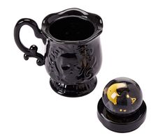 a black coffee mug with a yellow face on the side and a black cup next to it