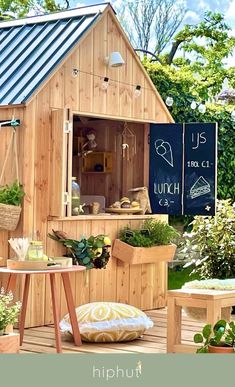 a small wooden building sitting on top of a lush green field with lots of plants