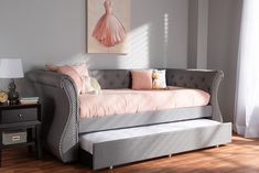 a daybed with pink and gray pillows in a room next to a painting on the wall