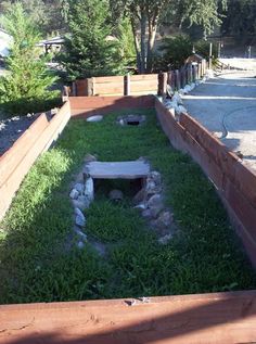 an open fire pit in the middle of a yard with rocks and grass around it