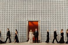 a group of people standing in front of a red door with white latticed walls