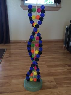 there is a sculpture made out of plastic balls on the floor in front of a window