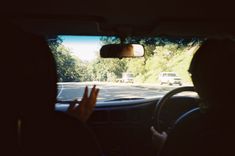 a person driving down the road with their hand up