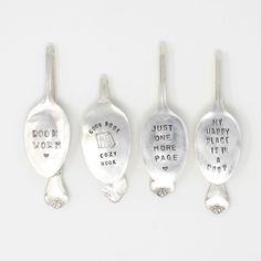 four spoons with words on them are shown in three different styles and sizes, one has