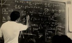 a man writing on a blackboard with lots of calculations