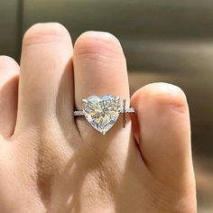 a woman's hand holding a heart shaped diamond ring