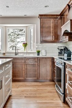 a large kitchen with wooden cabinets and stainless steel appliances on the counter top, along with hardwood flooring