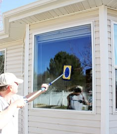 a man is painting the outside of a house with blue and yellow paint on it