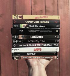 a stack of movies sitting on top of each other in front of a wooden wall