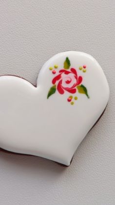 a white heart with red and yellow flowers on the inside is attached to a wall