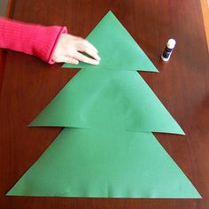 a person making a christmas tree out of green paper