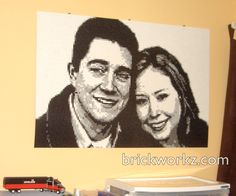 a lego portrait of a man and woman on the wall next to a toy train