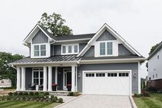 a gray house with white trim and two garage doors on the front door is shown