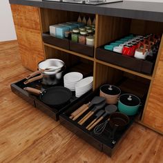 an open drawer with pots, pans and utensils in it on a wooden floor