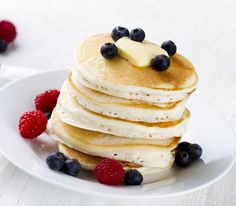 a stack of pancakes topped with butter and blueberries